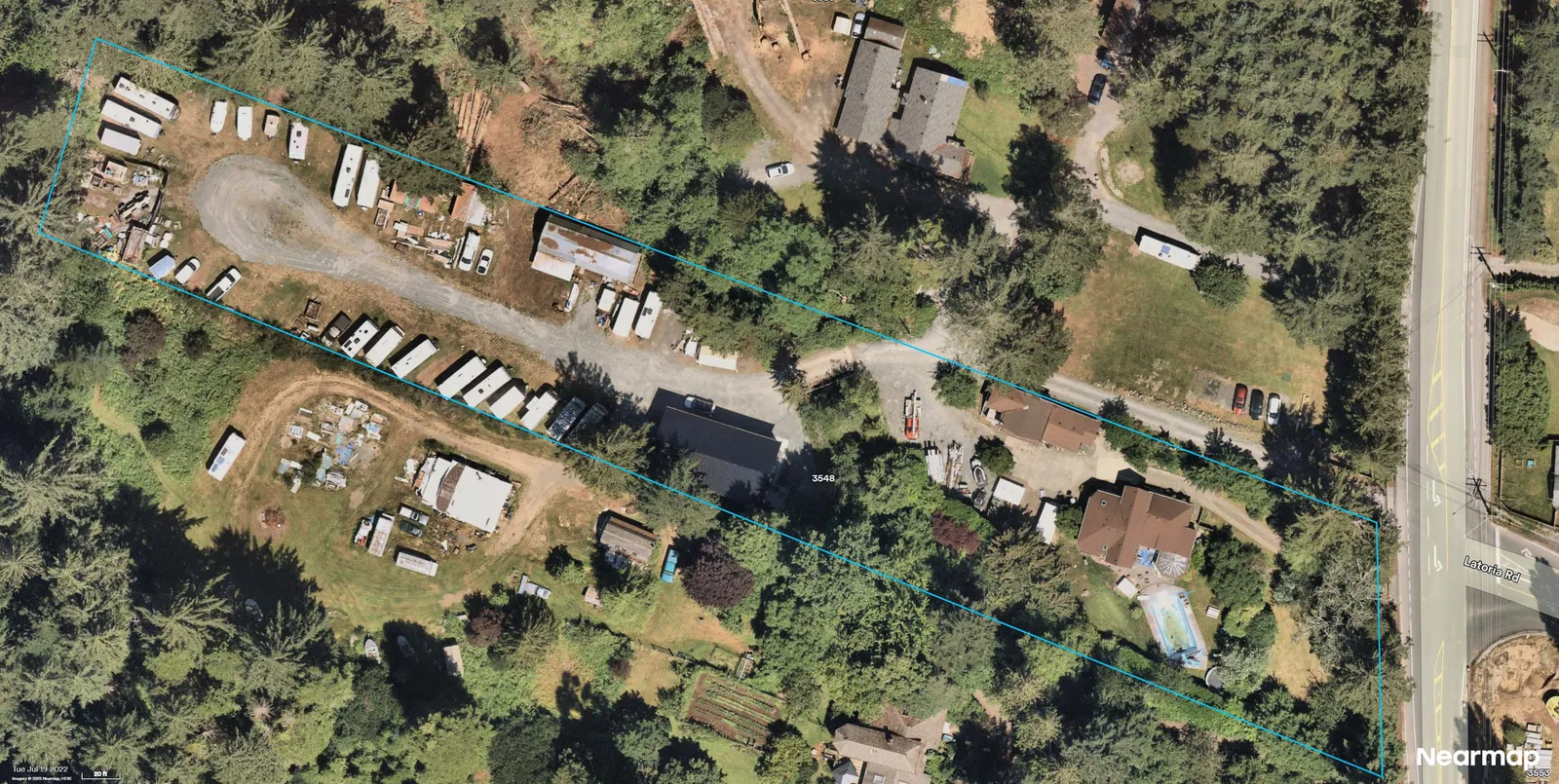 Aerial photograph showing the parcel outlined in blue with trailers/RVs and storage areas along the central drive; a larger building appears within the western portion of the parcel; residence and pool near Latoria Rd on the east side.